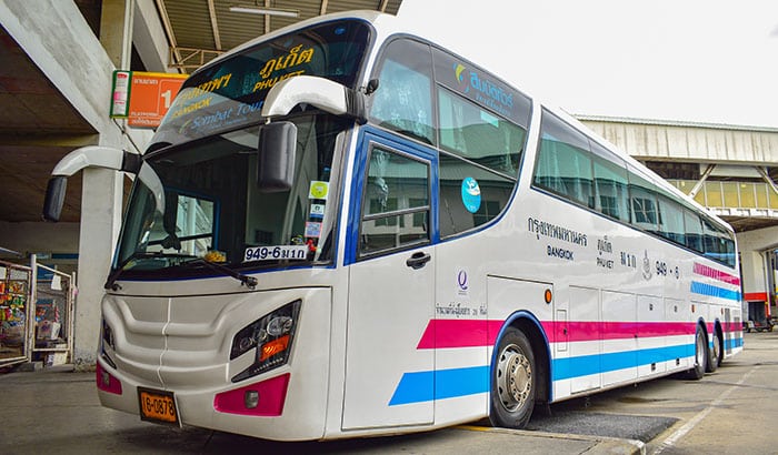 Autobús de la compañía Sombat Tour estacionado en la Terminal Sur de Bangkok, mostrando características franjas azules y moradas, operando entre Phuket y Bangkok.